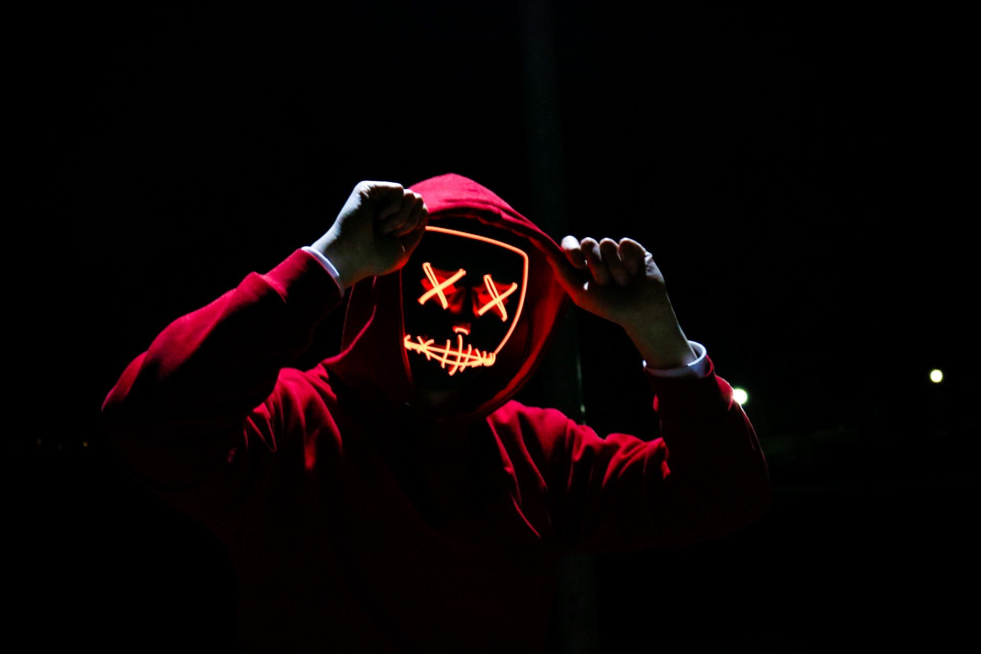 person in red hoodie with glowing skeletal mask on face