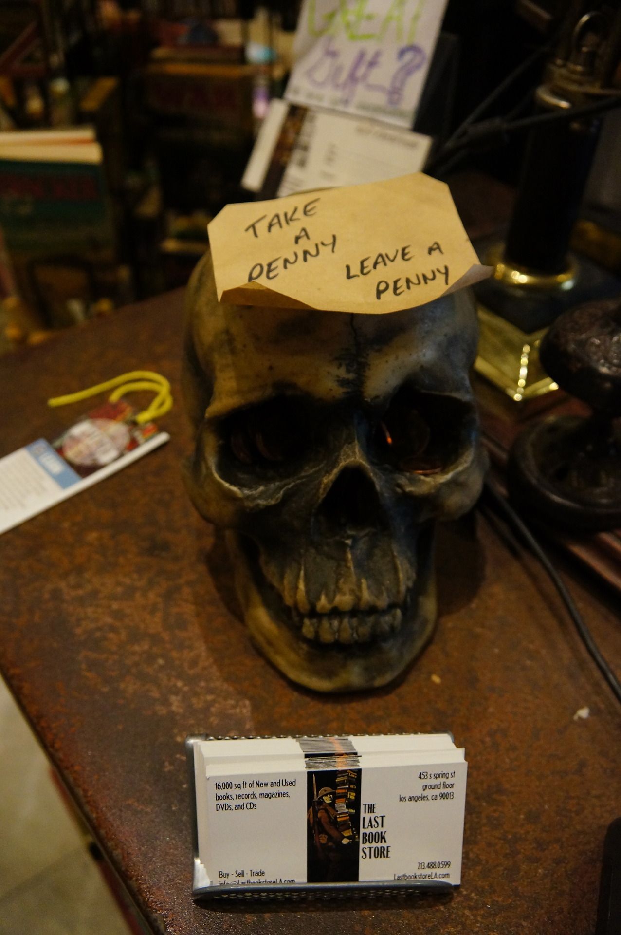 black skull with a post-it stuck on its head, saying 'take a penny, leave a penny'