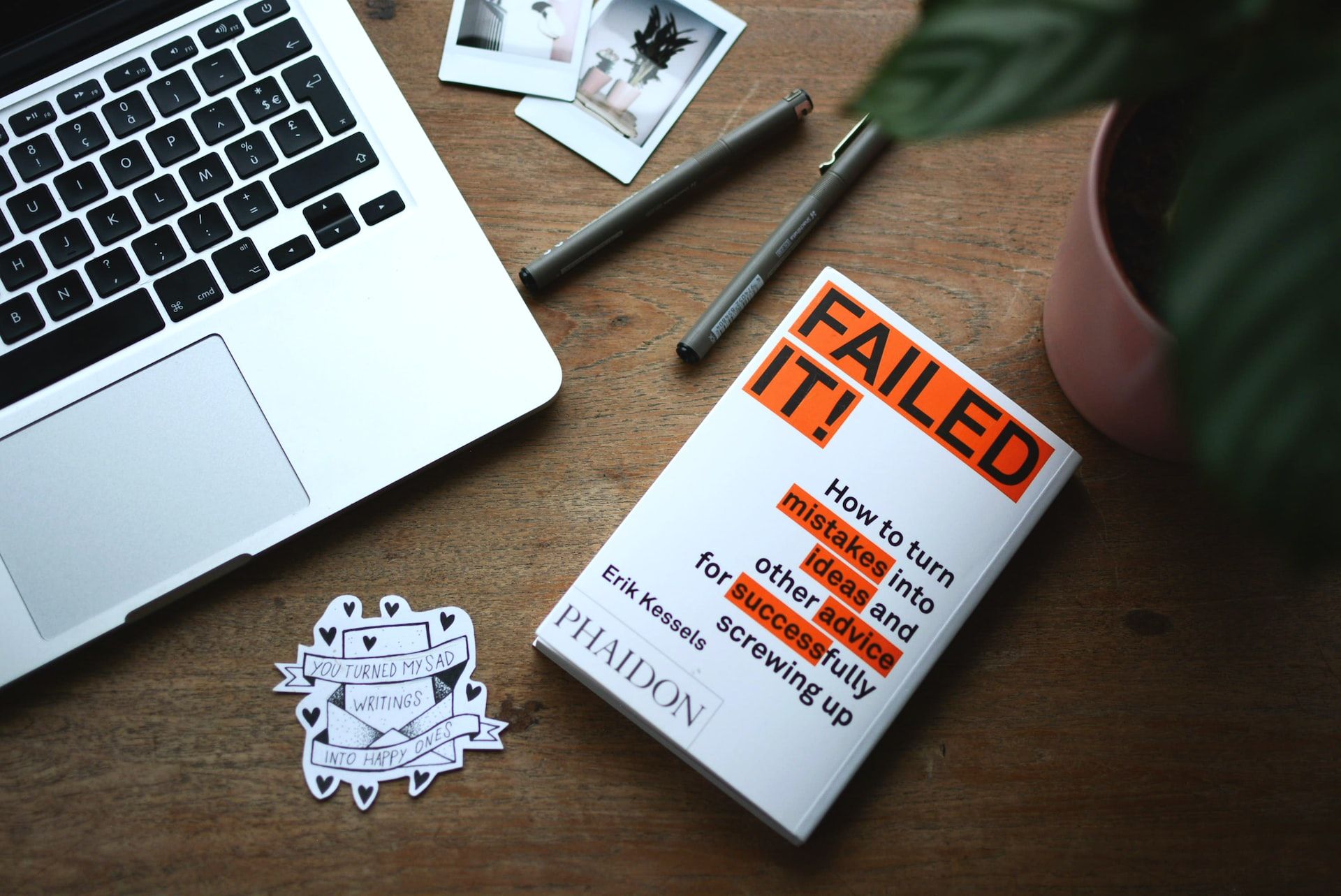 paperback copy of 'Failed It!' by Erik Kessels places beside a MacBook laptop on a writing table