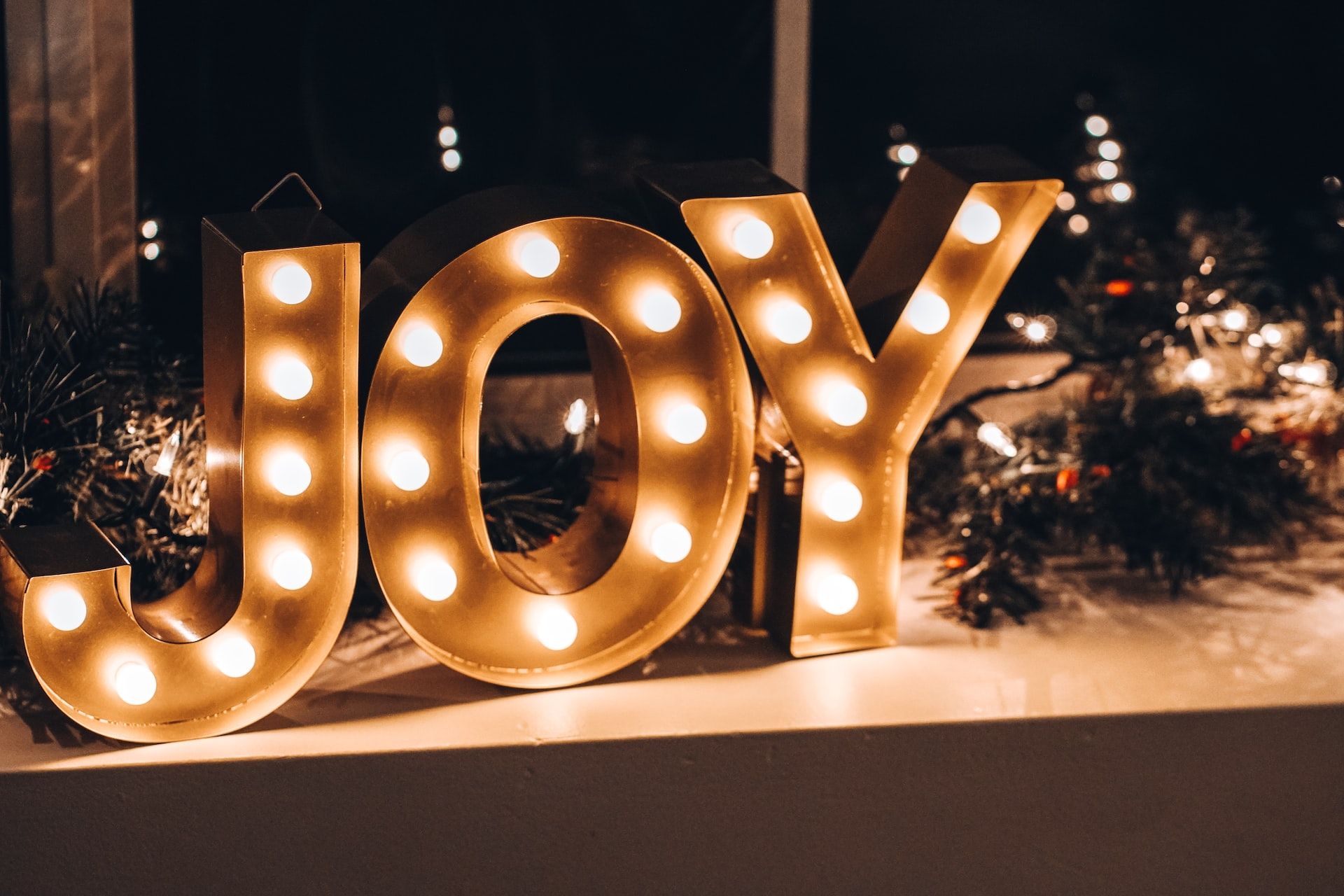 large uppercase letters spelling joy and lit with light bulbs