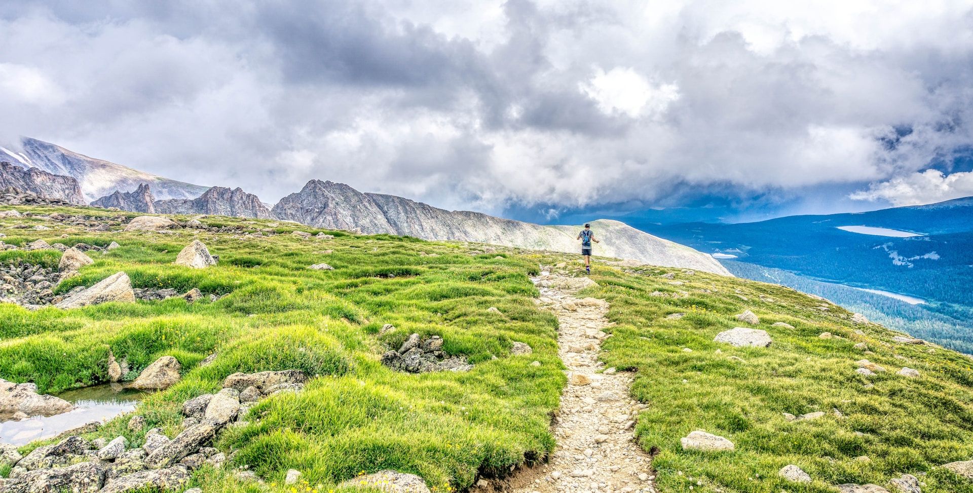 man running on a trail in the mountains under a cloudy sky
