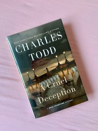 hardback copy of A Cruel Deception by Charles Todd featuring a bridge over water at twilight