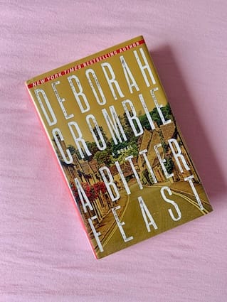 hardback copy of A Bitter Feast by Deborah Crombie featuring a country road in an English village
