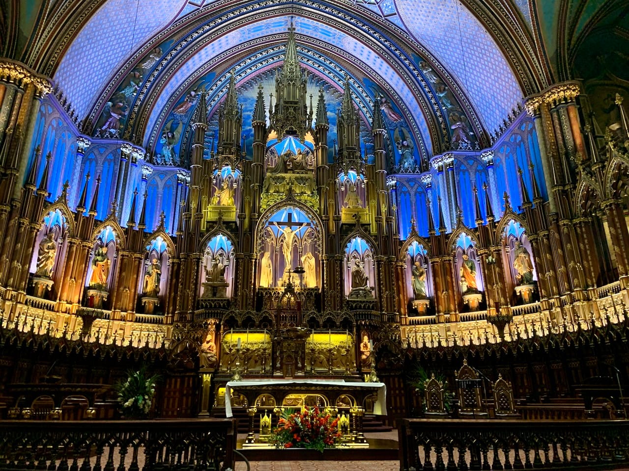 interior of the Notre-Dame Basilica of Montreal featuring sculptures of Jesus Christ and various saints under an intricate dome