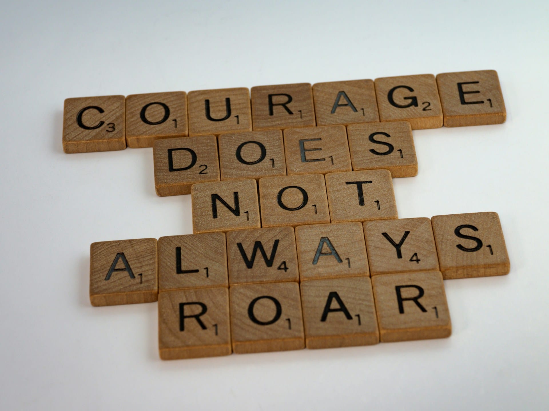 Scrabble letters arranged to read 'Courage does not always roar.'