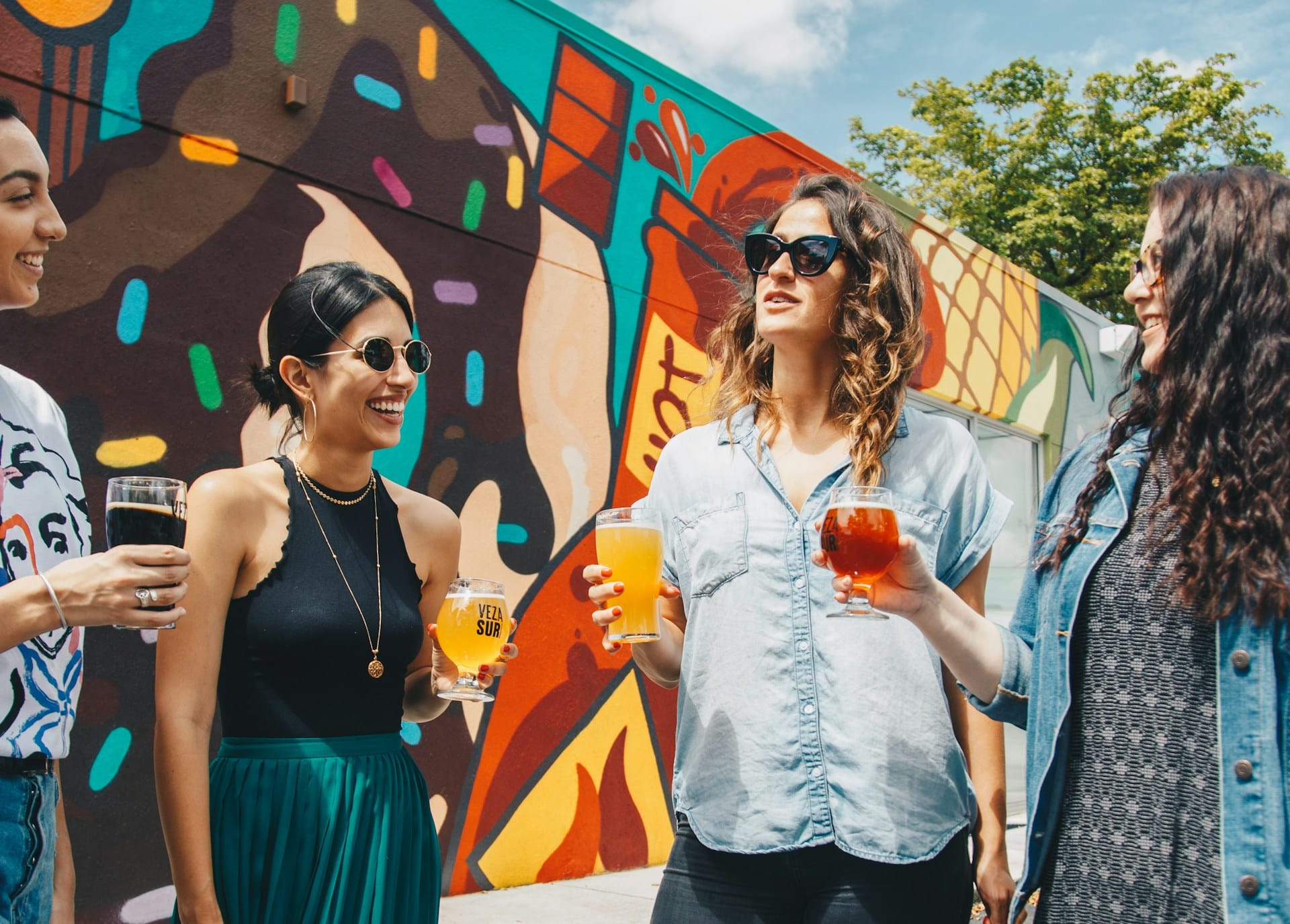 four women holding drinks and laughing