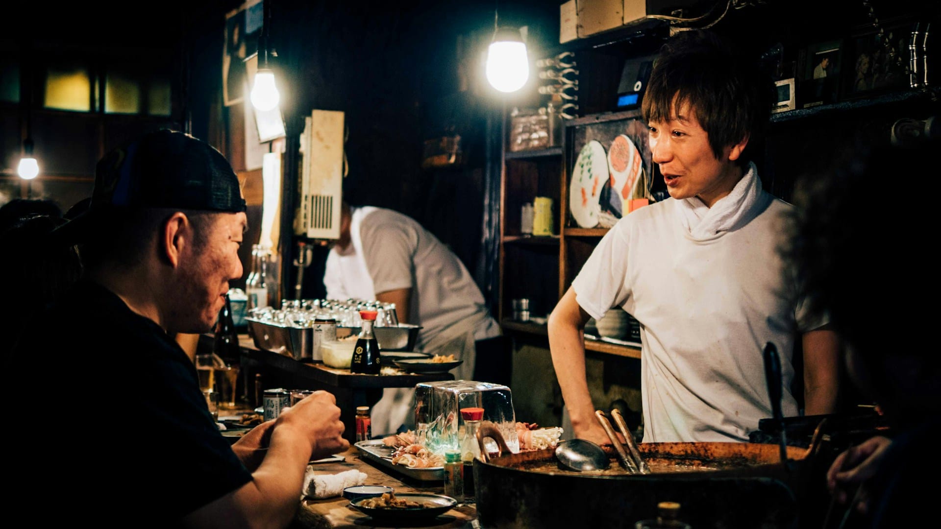 chef in a small food stall smiling at a customer from behind the counter