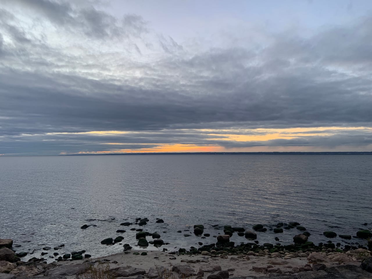 an orange glow in the horizon over Lake Ontario at the break of dawn