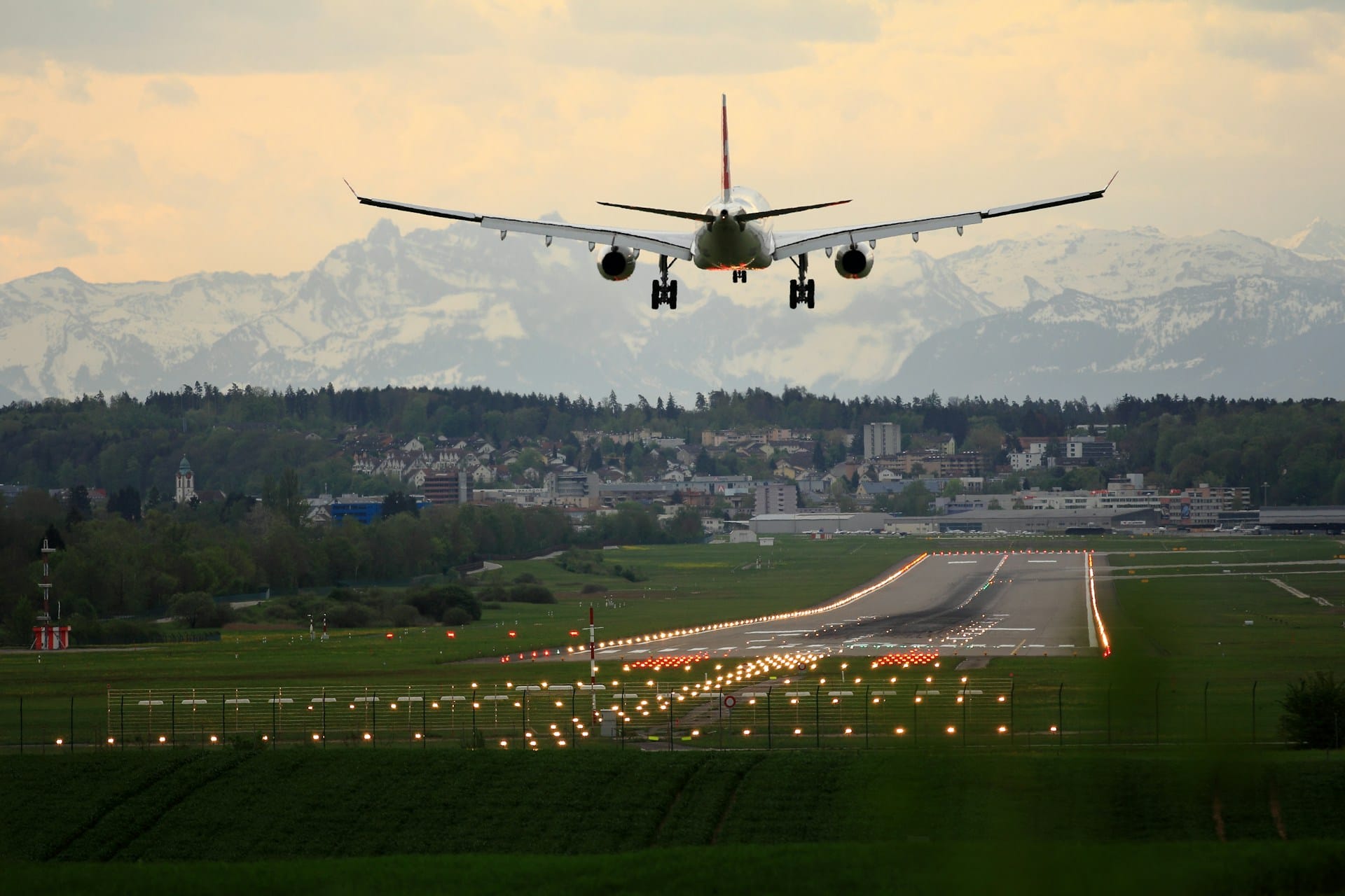 a plane heading towards runway against a backdrop of snow-capped mountains
