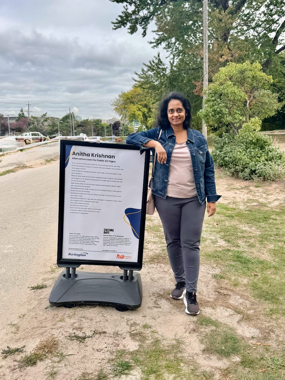 Image of me - a woman - standing against a public art installation featuring a short story of mine