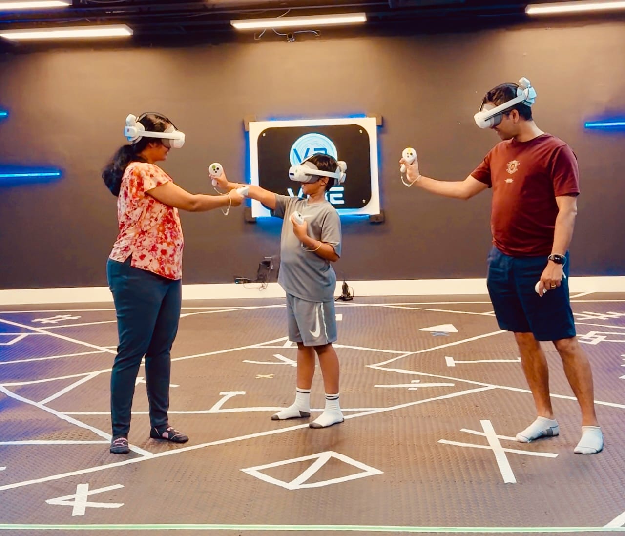 Me, my husband, and our child wearing Virtual Reality headsets and immersed in a game in an indoor room