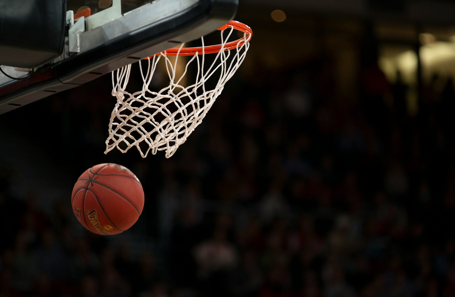 a basketball falling through a hoop against a dark background