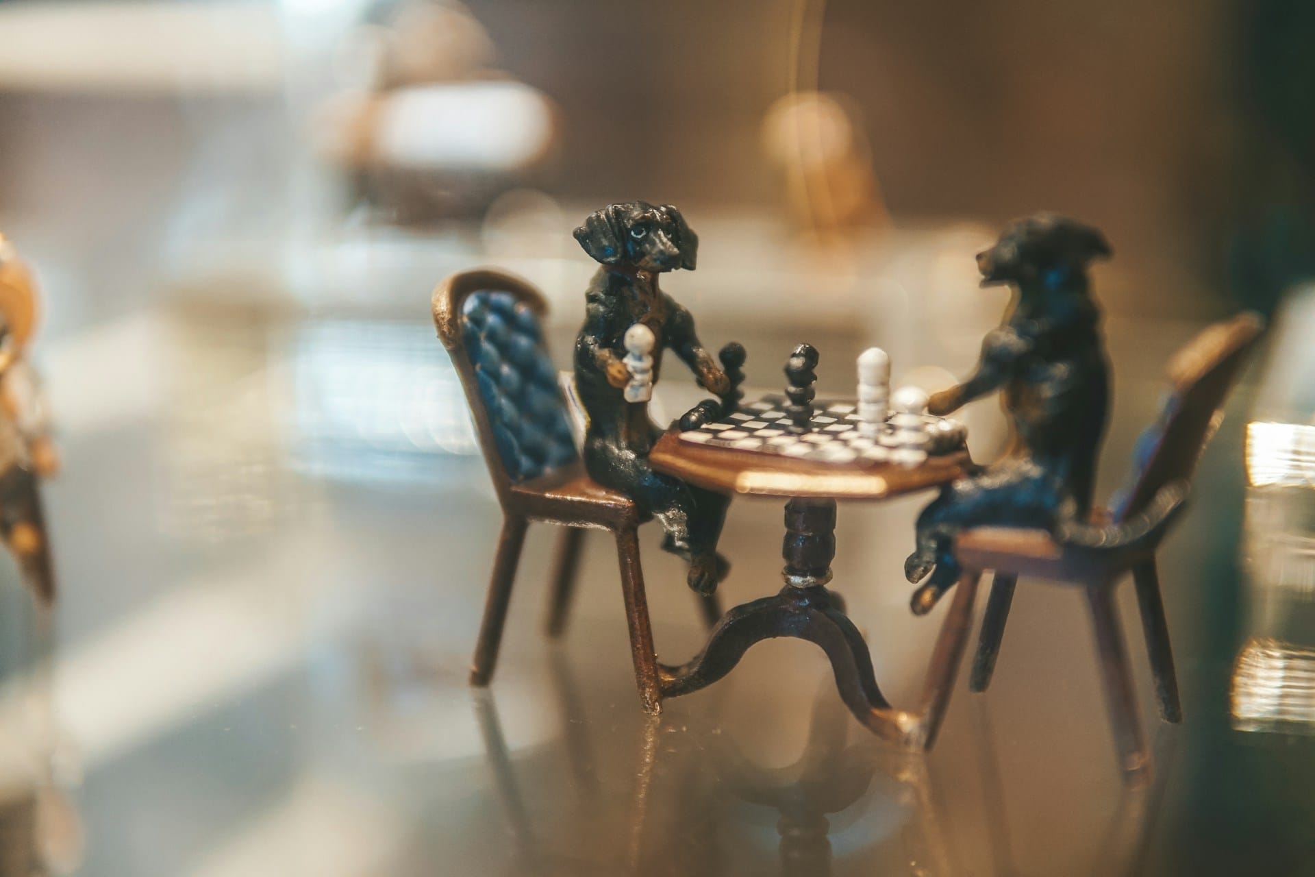 a miniature chess game played by two figurines of dogs set upon a table