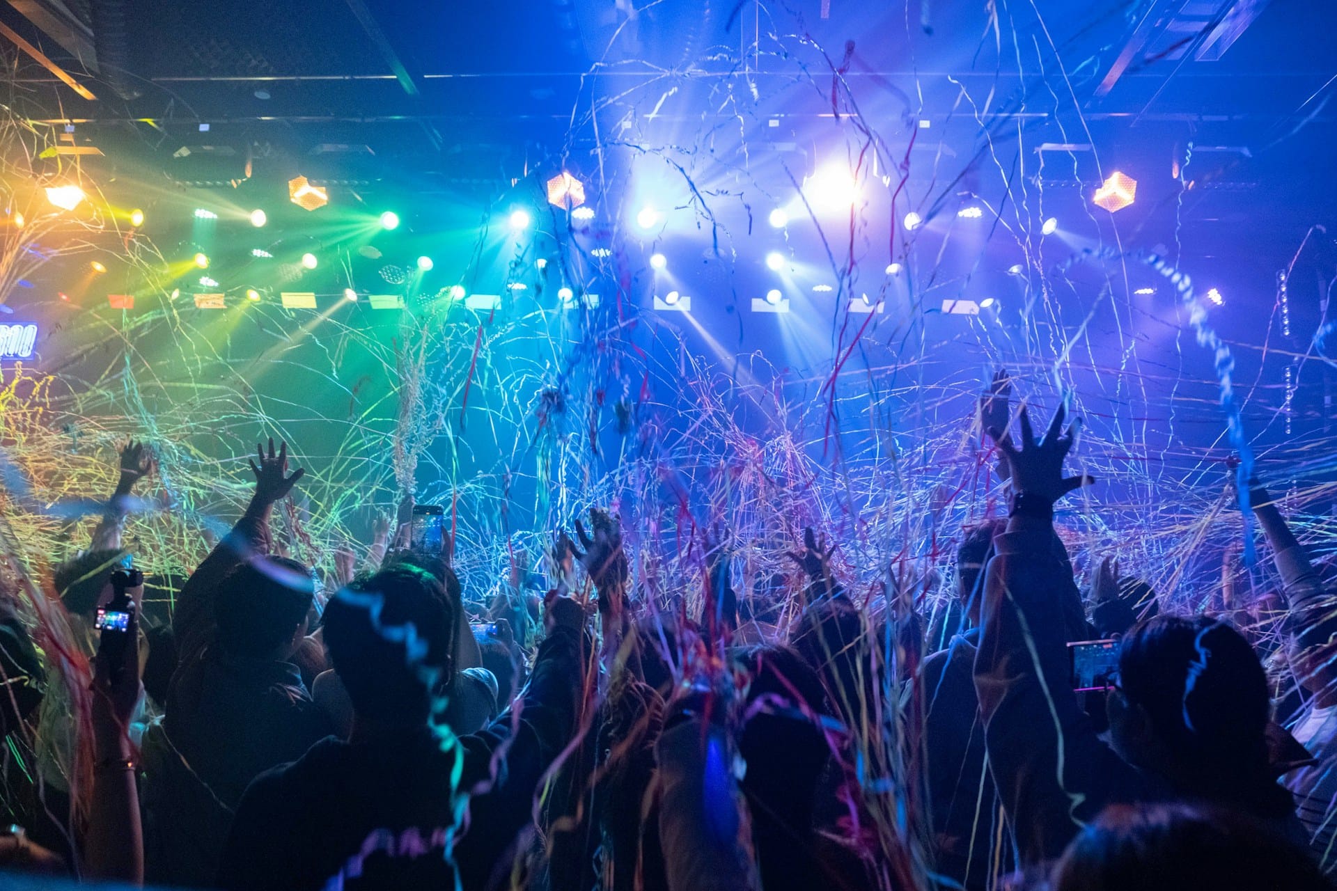 crowd with hands up in the air in a concert with confetti falling on them