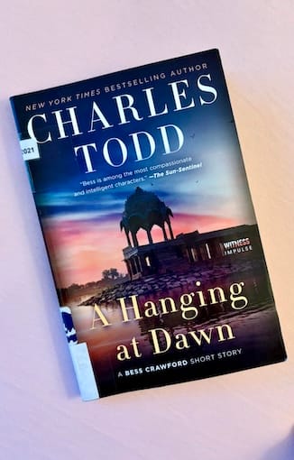 hardback copy of A Hanging At Dawn by Charles Todd featuring a lakeside single-storeyed stone structure topped with an Indian minaret