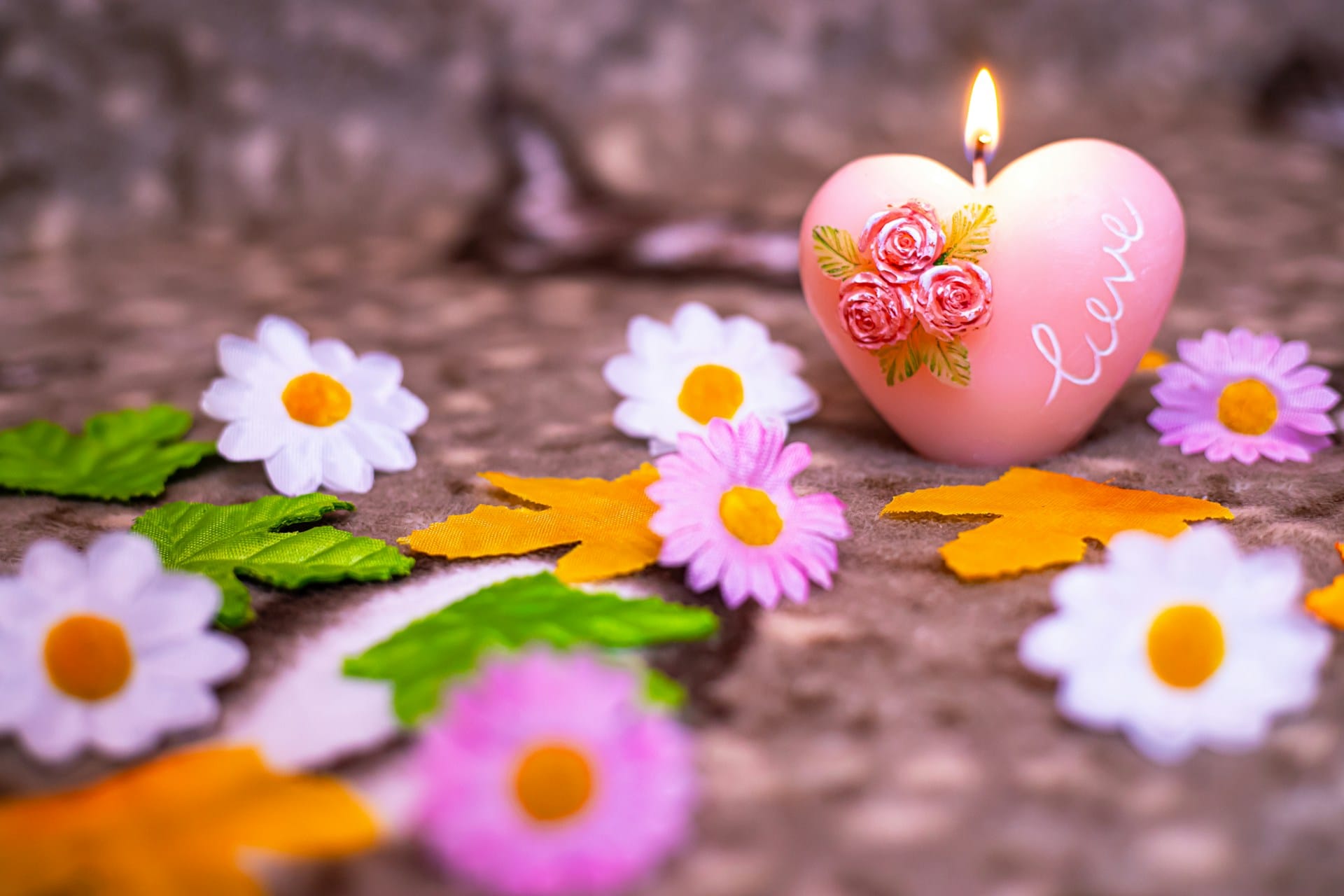 heart-shaped candle surrounded by flowers and autumn leaves