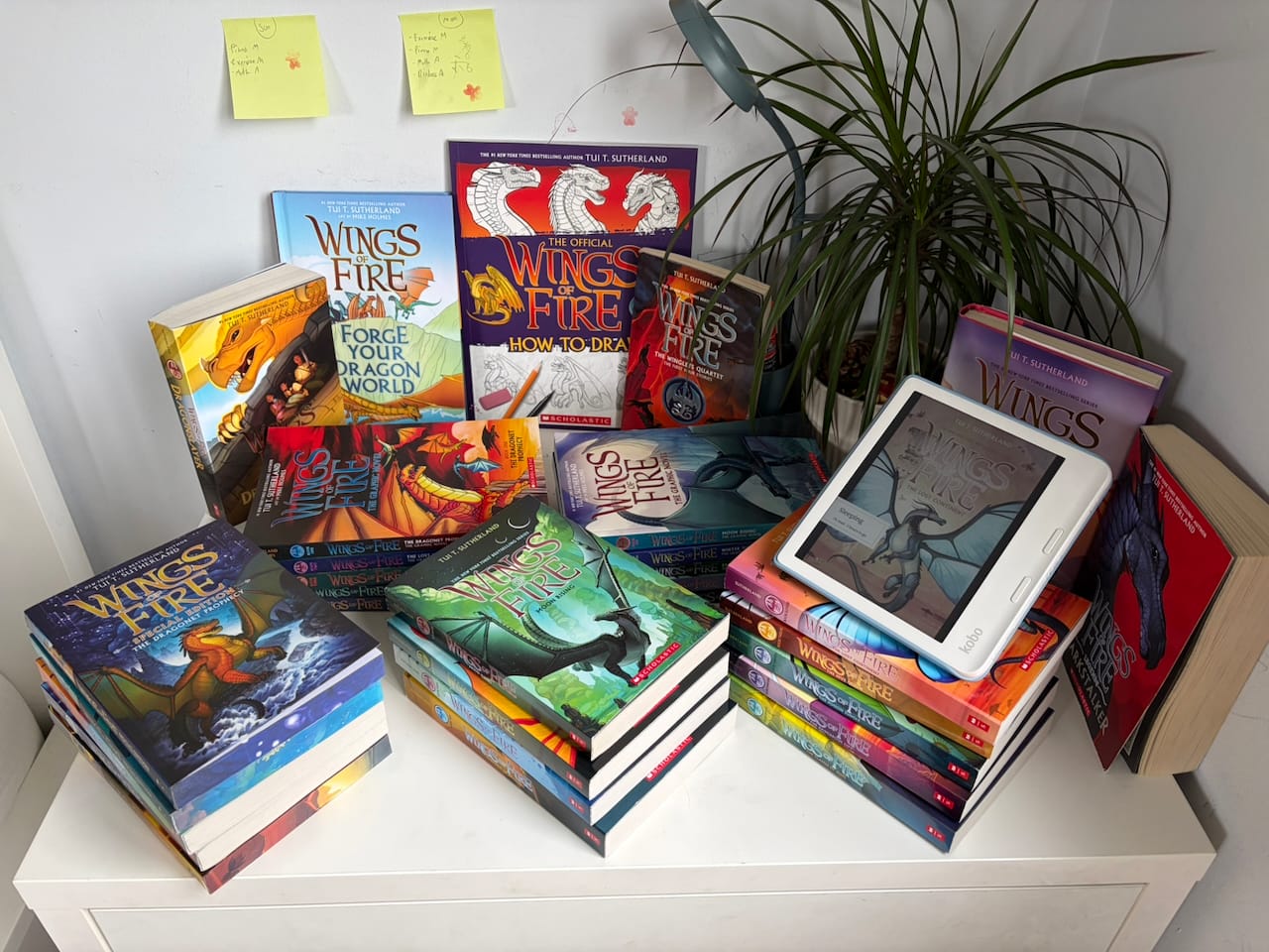 a collection of Wings Of Fire novels and graphic novels atop a table