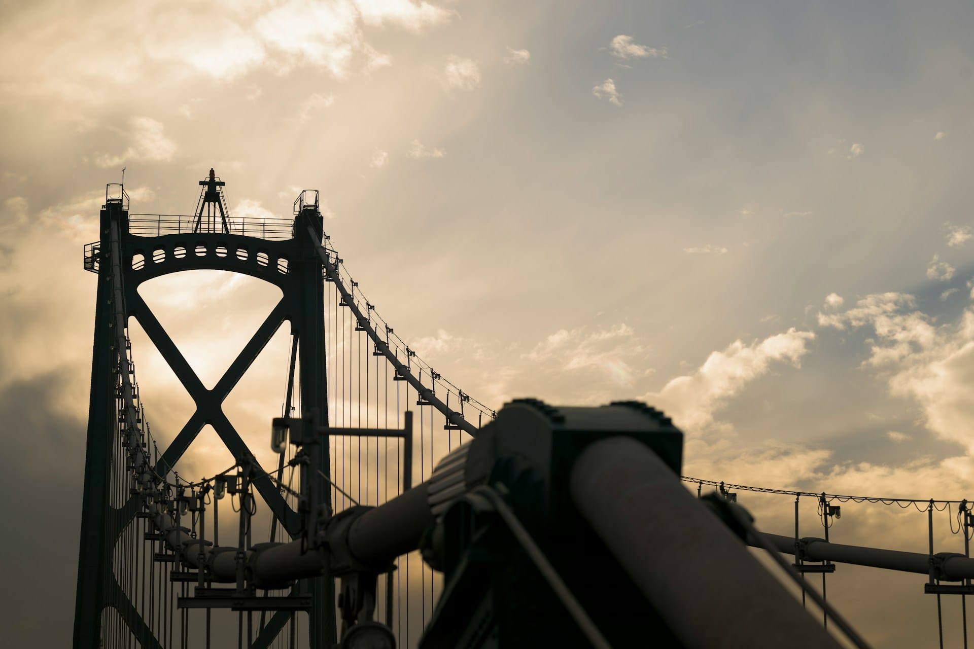 suspension bridge against a cloudy sky at sunset