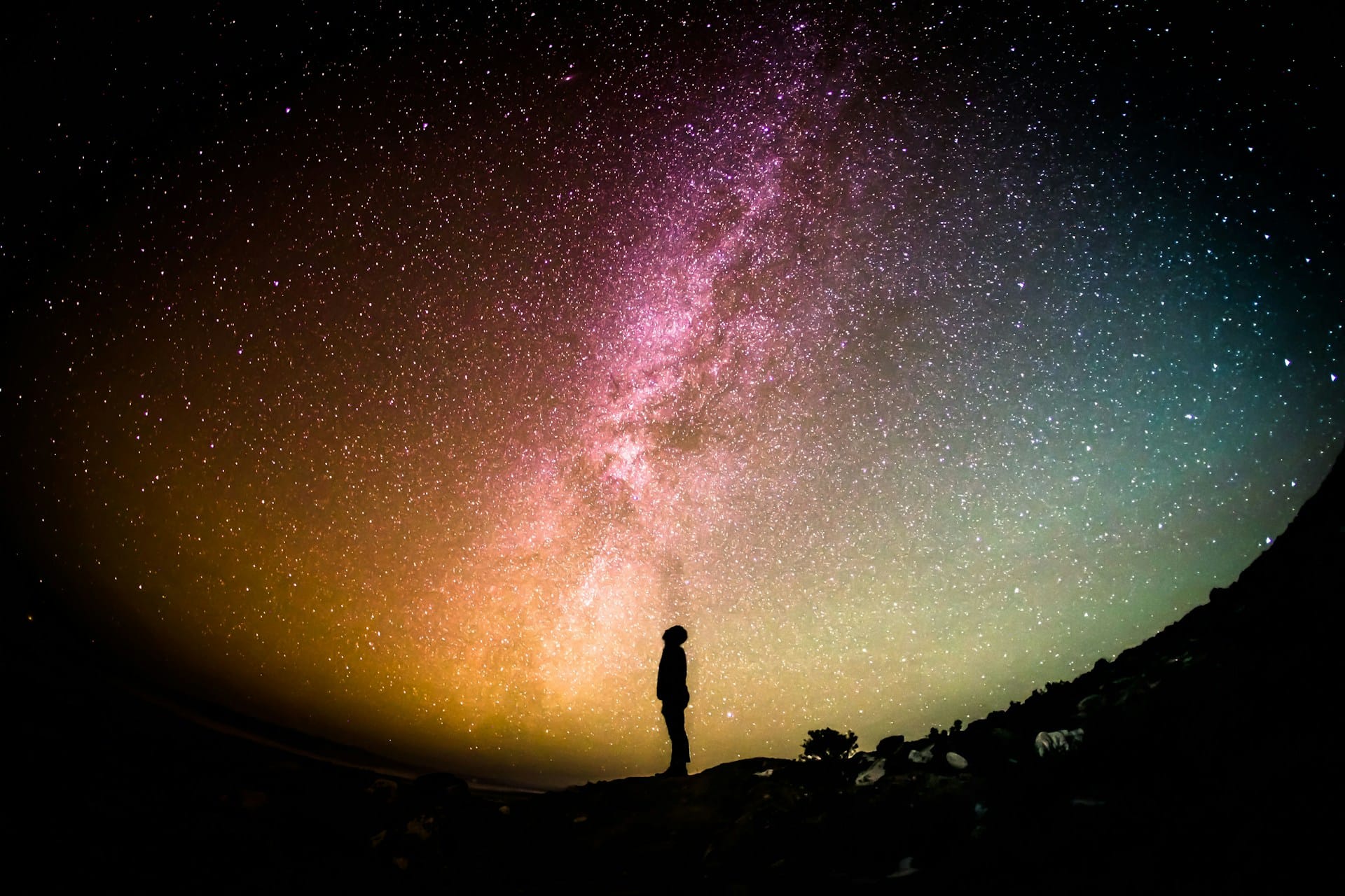 silhouette of a man looking up at a starry sky in the nighttime