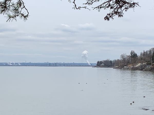 plume of smoke rising from a factory chimney on the far shore of Lake Ontario