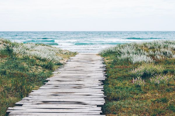 a wooden path to the beach and blue waters beyond