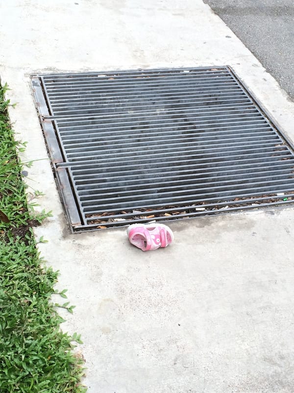 a pink baby shoe abandoned on a pavement