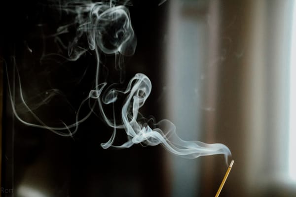 white tendrils of smoke rising from an incense stick