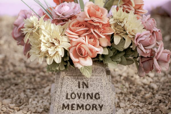 pink and white flowers on a grey concrete tomb with the words 'In Loving Memory'