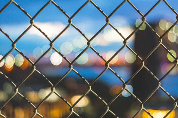 woke view of city lights on the other side of a chicken wire fence