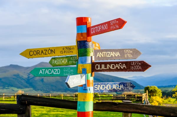colourful signpost with arrows pointing towards 9 different cities bearing their names and distances