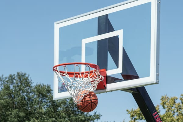 basketball falling through the hoop against a backdrop of blue sky