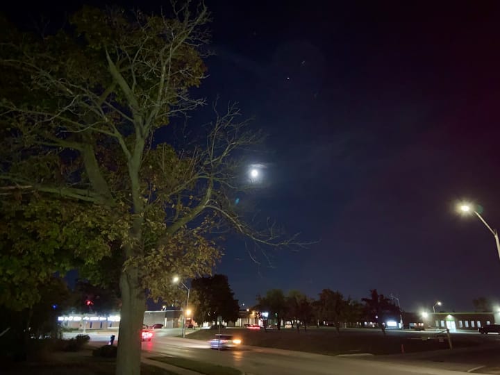 full moon shining above city lights