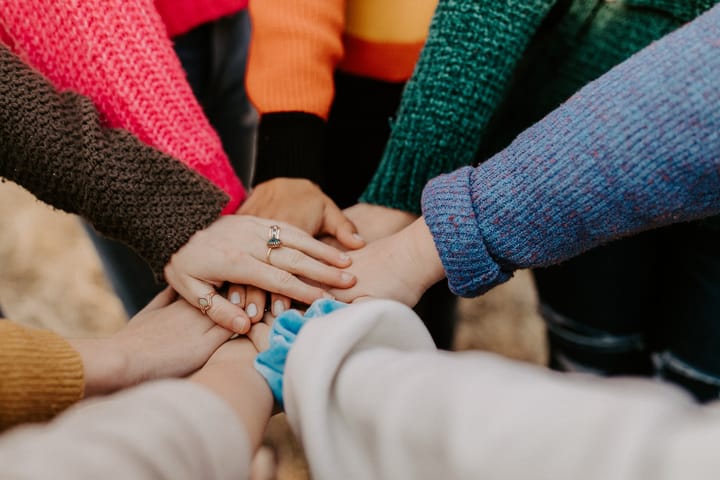 eight people placing their hands on top of each other's