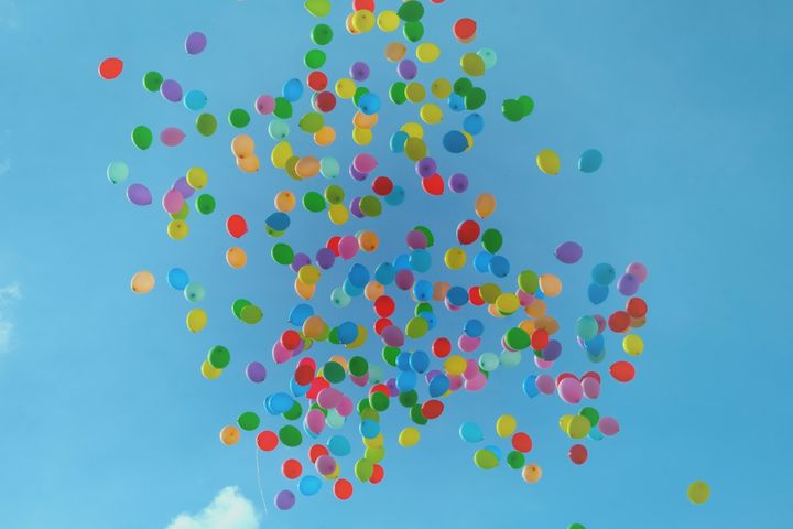 multicoloured balloons flying in a bright blue sky