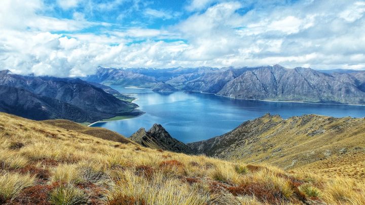 blue lake surrounded by bare mountains under a blue sky with white clouds