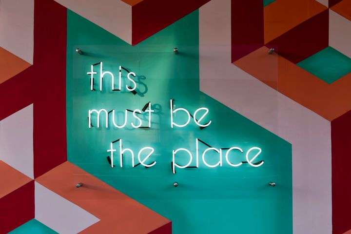 white lights on a colourful board stating 'this must be the place'