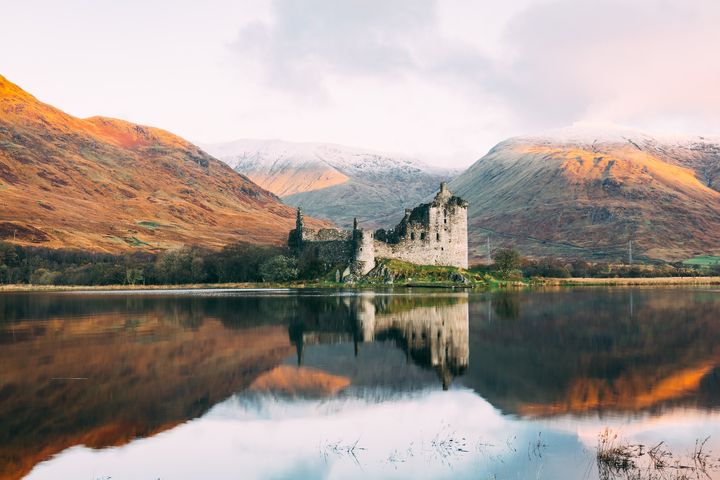 castle ruins by a lakeside at the foot of hills