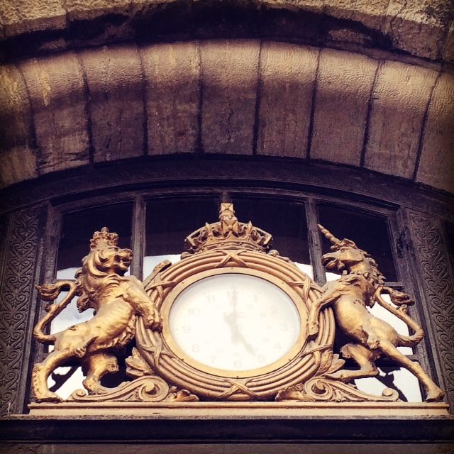 a clock atop a building flanked by a statue of a unicorn and a lion