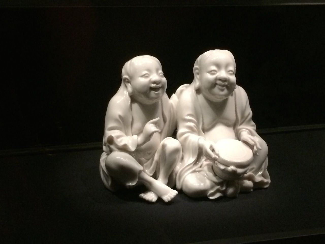 two white statues of laughing Buddhas