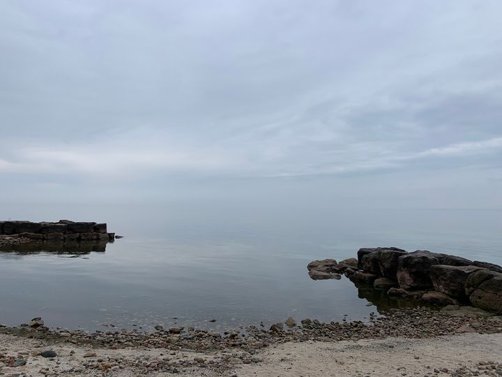 view of a lake under a misty grey sky blurring the boundaries between water and sky