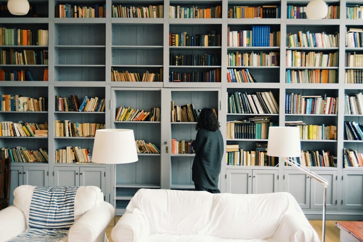 woman browsing through a shelf of books, trying to find something to read