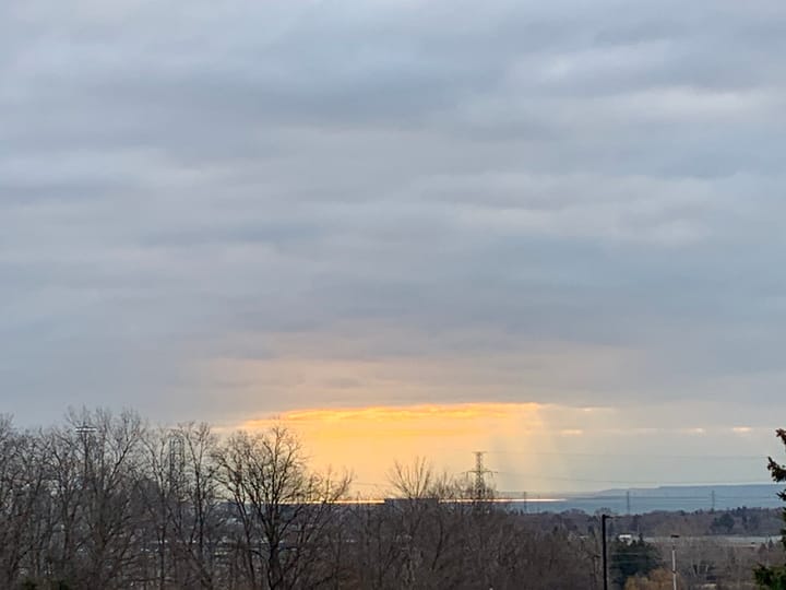 sunlight filtering through a circular gap in the clouds casting a cylindrical pool of light on the lake below