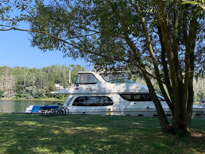 a yacht named 'Liquid Wisdom' moored beside a green lawn