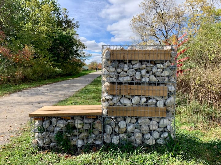 a caged enclosure of rocks set on a grassy sidewalk