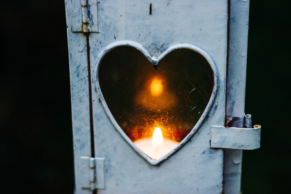 Image of a candle in a blue-grey metal lantern with a heart-shaped glass front