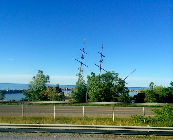 masts of a stranded ship visible behind treetops against a bright blue sky