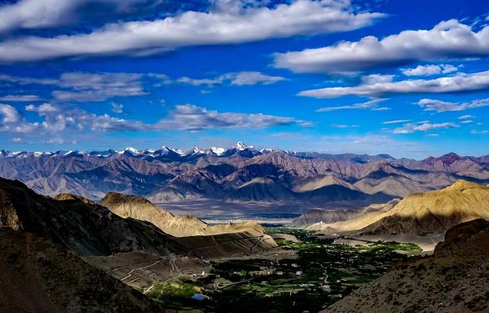 panoramic view of the Himalayan mountains under bright blue skies and white clouds